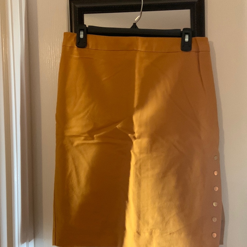 Mustard colored skirt with gold buttons on the bottom